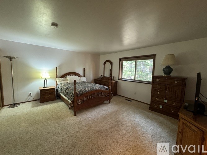 A bedroom with a bed, dresser, and window.