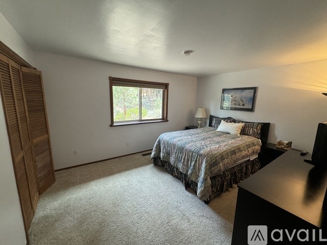 A bedroom with a bed, nightstand, and window.