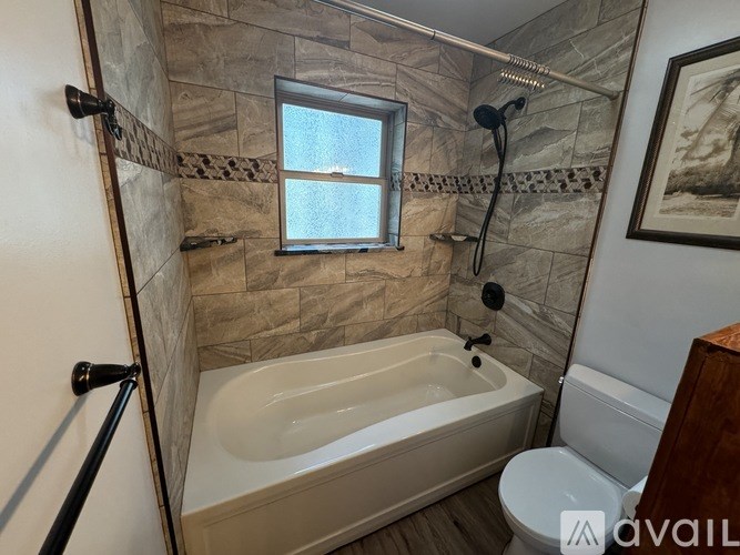 A bathroom with a tub, toilet, and window.