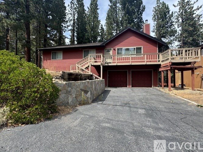 A red house with a stone wall and a driveway in front.