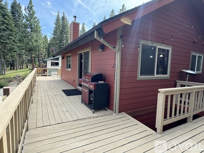 A red house with a wooden deck and a grill.