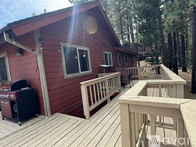 A red wooden house with a deck and a hot tub.