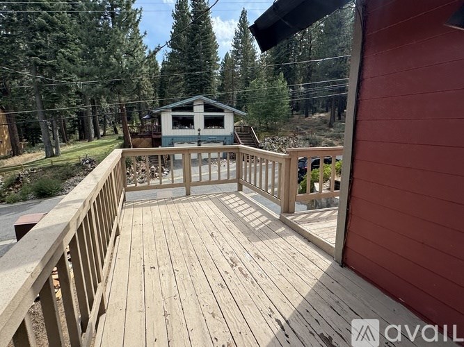 A wooden deck with a railing and a small building in the background.