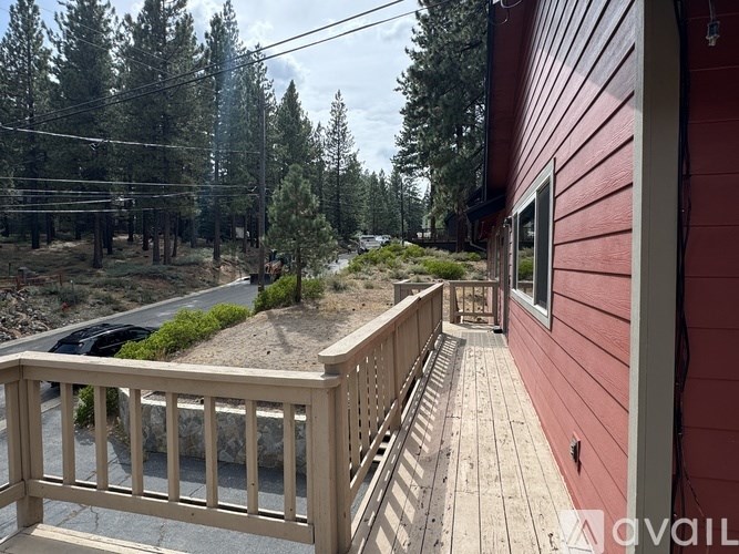 A red house with a deck and a view of a forest.