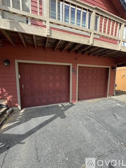 A red house with a balcony and two garage doors.
