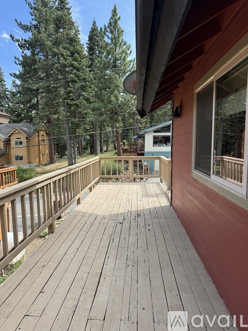 A wooden deck with a railing and a small table in the middle.