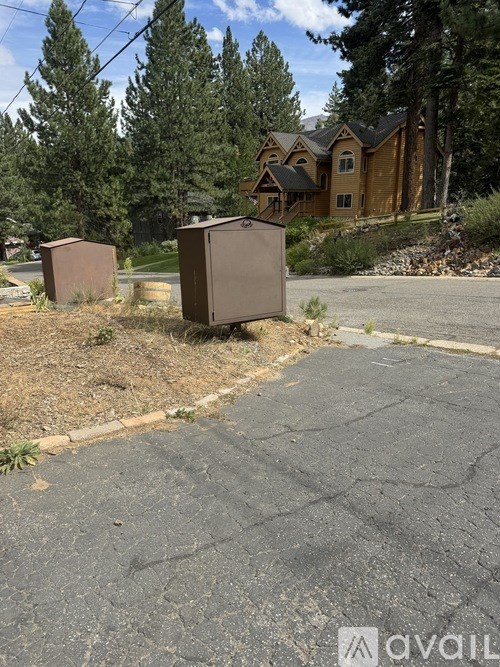 Two brown refrigerators are placed on a grassy area in front of a house.