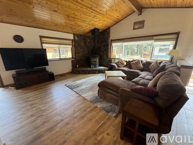 A living room with a wooden floor and a stone fireplace.