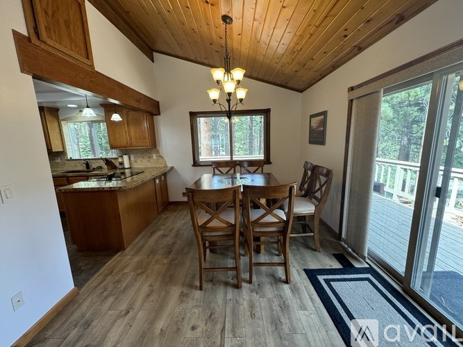 A wooden dining table with chairs is in the middle of a room with a wooden ceiling and floor.