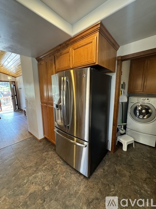 A kitchen with a stainless steel refrigerator and wooden cabinets.