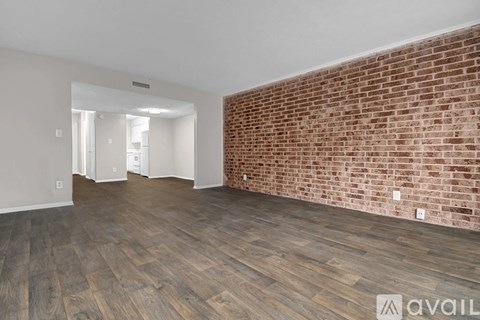 A room with wooden flooring and a brick wall.
