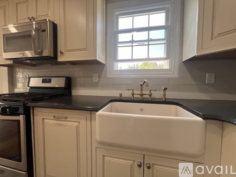 A kitchen with a white sink and a window.