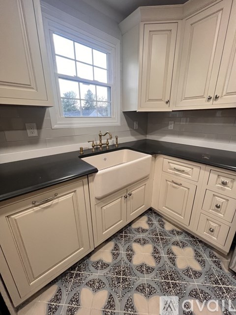 A kitchen with white cabinets and a black countertop.
