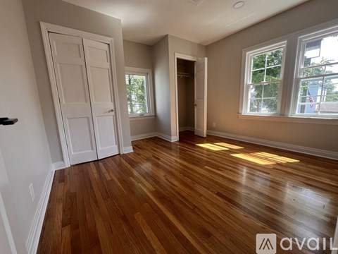 A room with wooden floors and two windows.