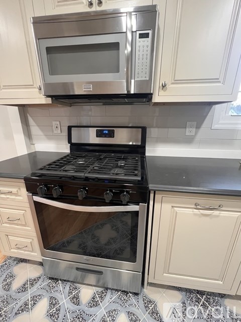 A black stove top oven with a silver microwave above it.