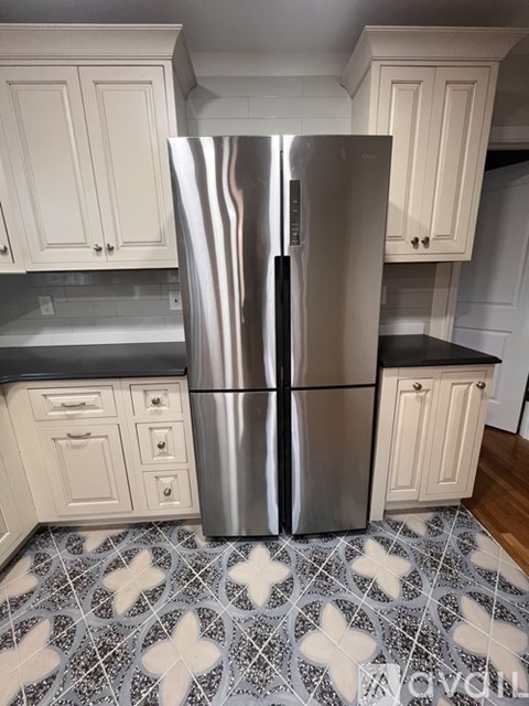 A kitchen with a stainless steel refrigerator and white cabinets.