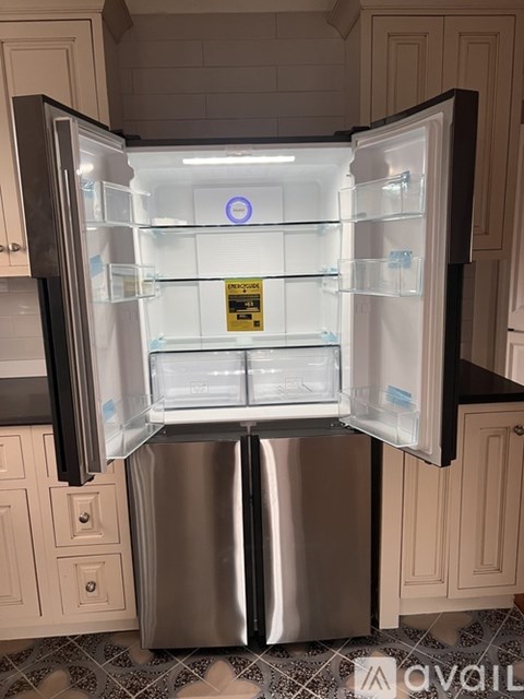 A stainless steel refrigerator with its door open in a kitchen.