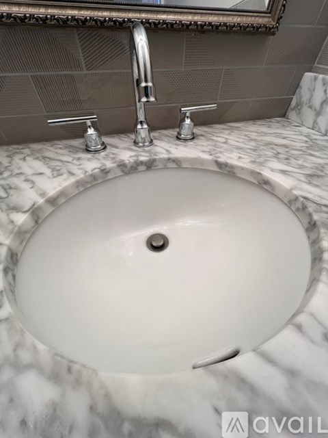 A white sink with a silver faucet and a mirror above it.