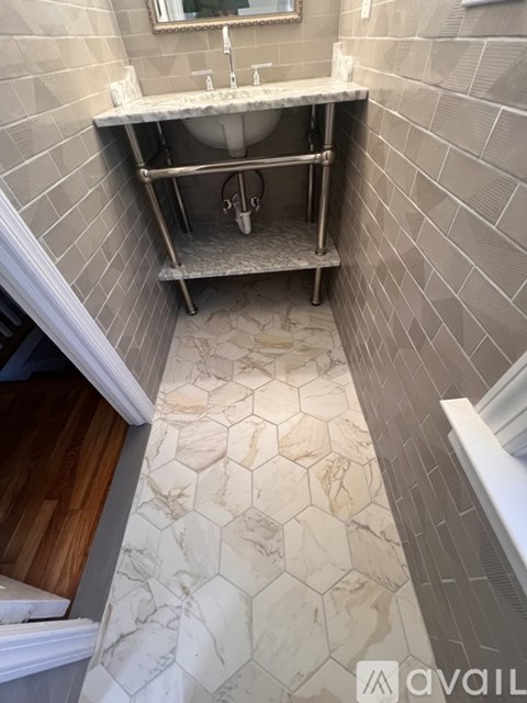A bathroom with a marble hexagon tile floor and a white sink.