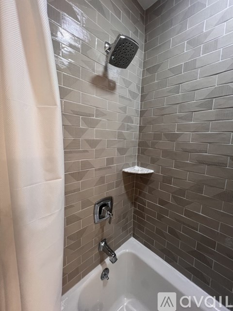 A shower area with a white tub and a shower head.