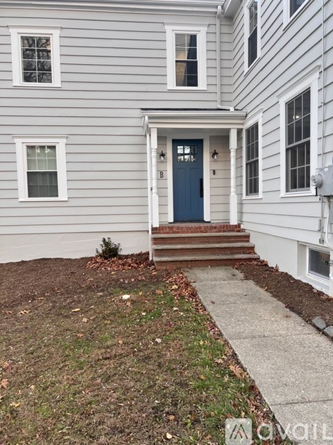 A grey house with a blue door and a small front yard.
