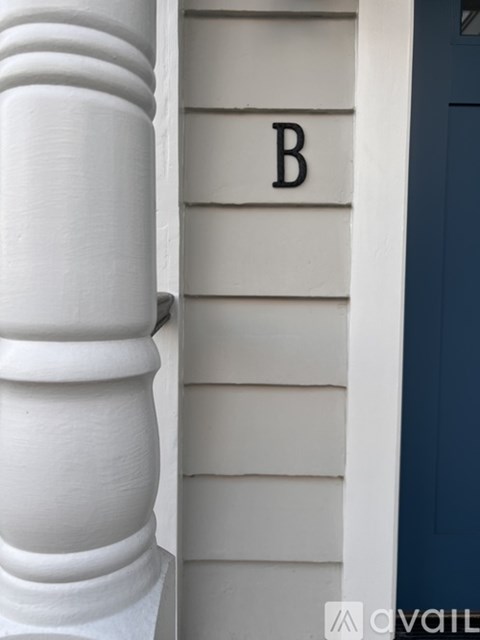 A white column next to a house with a blue door.