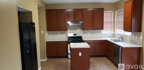 A kitchen with brown cabinets and a black refrigerator.