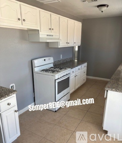 A kitchen with white cabinets and a stove top oven.