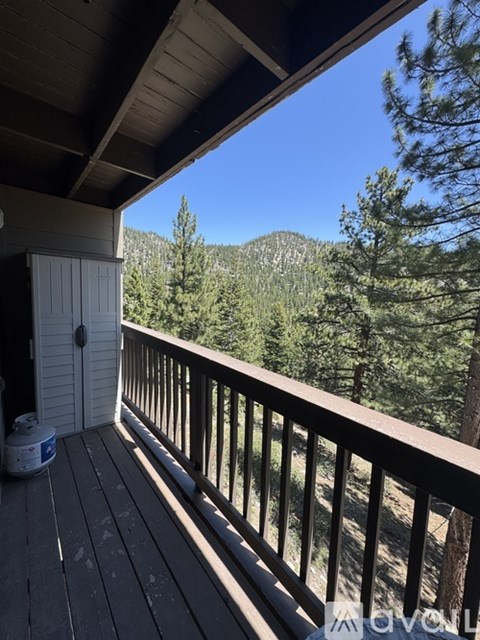 A deck with a view of a forest and mountains.