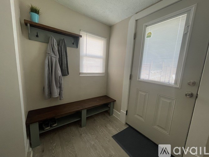 A small room with a bench and coat rack.