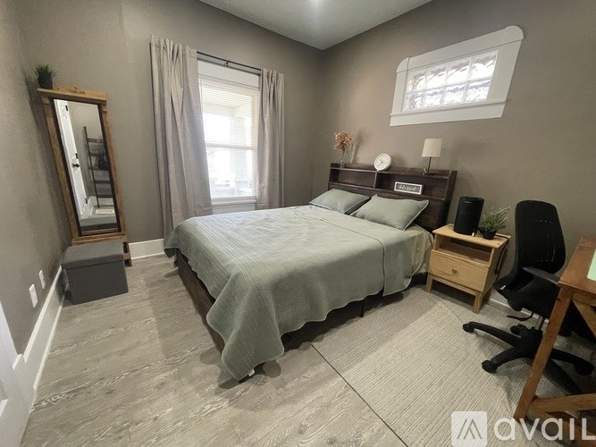 A bedroom with a bed, desk, chair, and window.