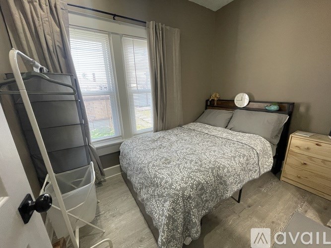 A bedroom with a bed, nightstand, and a window with curtains.