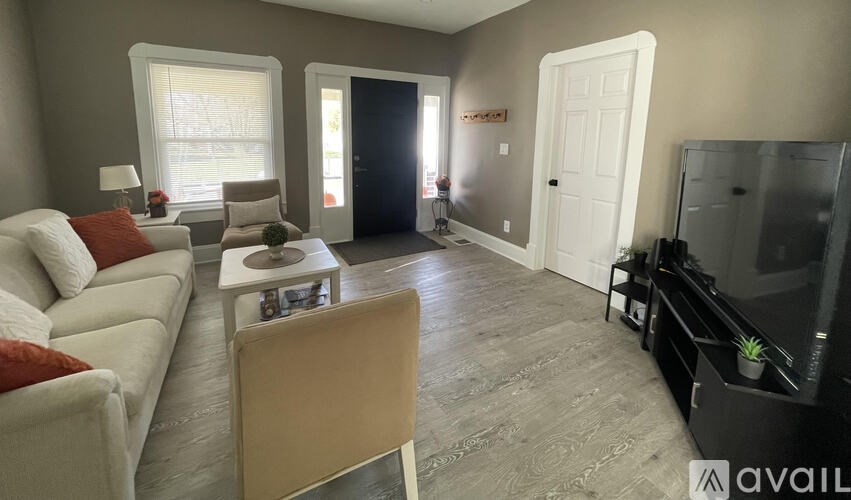 A living room with a white sofa, a wooden chair, a television, and a black cabinet.