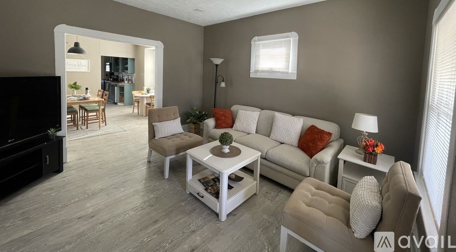 A living room with a grey sofa, a white coffee table, and a black television.