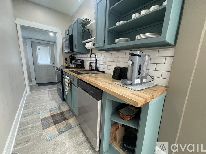 A kitchen with a wooden countertop and a tile backsplash.