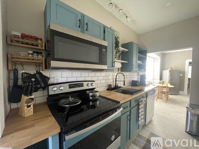 A kitchen with a black stove top oven and blue cabinets.