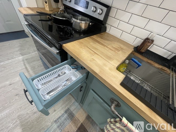 A kitchen with a black stove top oven and a wooden cutting board on the counter.