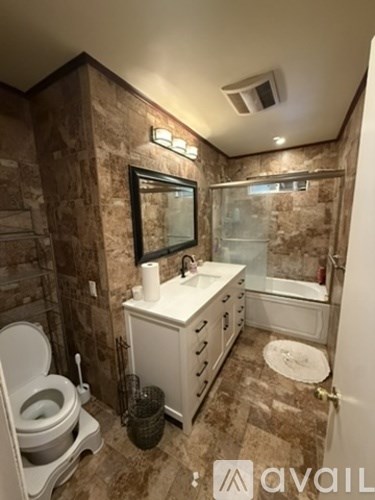 A bathroom with a toilet, sink, and a mirror.