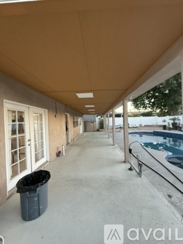 A long covered walkway with a trash can on the left side.
