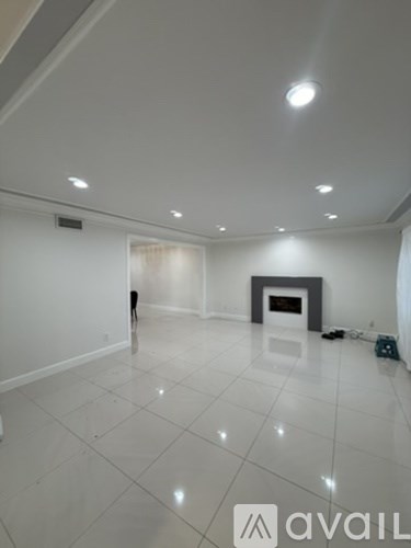 A spacious room with a fireplace and a white floor.