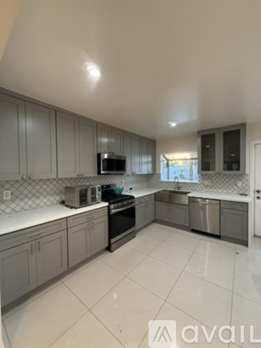 A kitchen with grey cabinets and a white counter top.