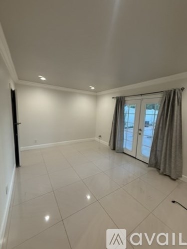 A spacious room with a sliding glass door and grey curtains.