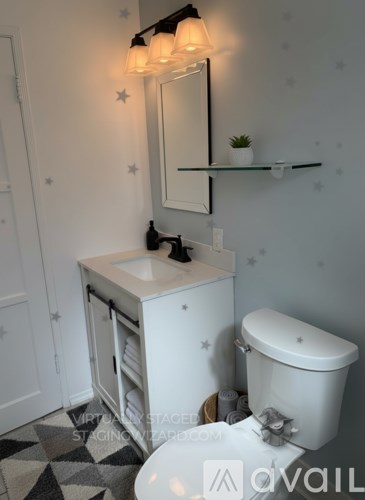 A white sink and toilet in a bathroom with a mirror and a shelf above it.