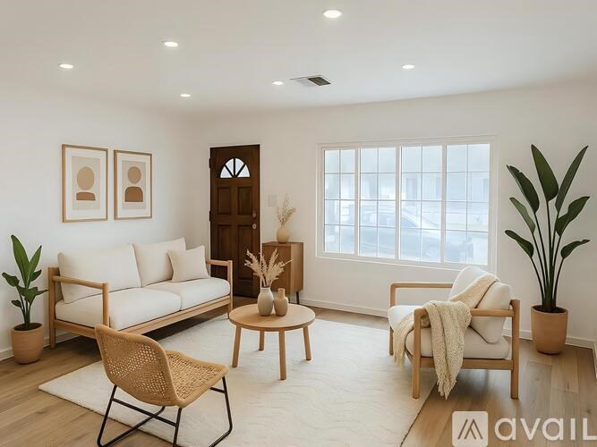 A living room with a white sofa, a wooden chair, a wooden table, and a potted plant.