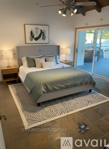 A bedroom with a bed, two lamps, and a painting on the wall.