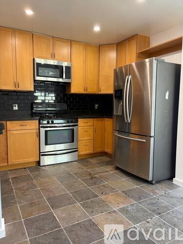 A kitchen with wooden cabinets and a stainless steel refrigerator.