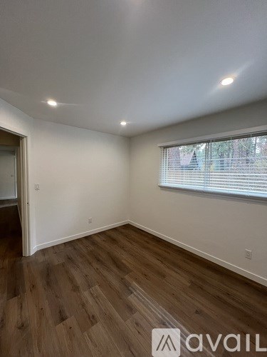 A room with wooden flooring and a window with blinds.