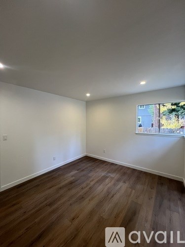 A room with wooden flooring and a window showing an outdoor view.