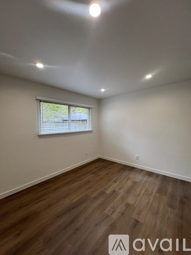 A room with wooden flooring and a window with blinds.