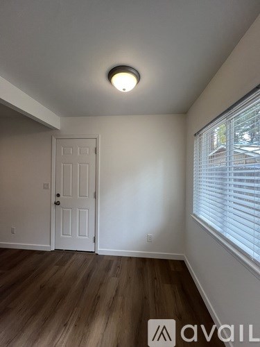 A room with a white door and wooden flooring.
